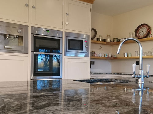 Owery show-stopper kitchen with black wave granite work tops and floor to ceiling tulip wood units